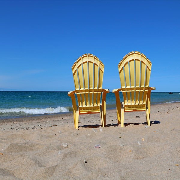 صندلی پلاستیکی ساحلی و دسته دار مقابل دریا و زرد رنگ