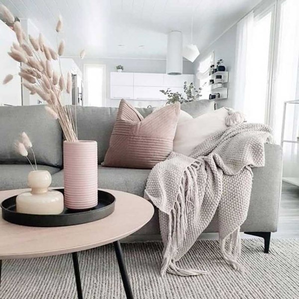 مبل راحتی طوسی رنگ که در اتاق و در مقابل یک میز قرار گرفته است و یک شال مبل نیز روی دسته آن قرار دارد.