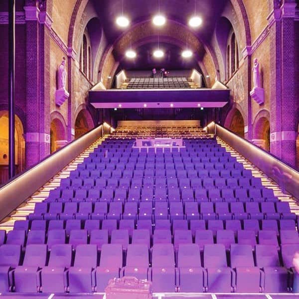 صندلی آمفی تئاتر بنفش در یک سالن با نور بنفش