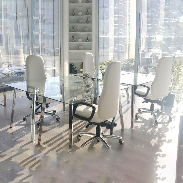 صندلی اداری سفید دورتادور میز شیشه ای در فضای اتاق